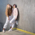 Dwie kobiety w pastelowych stylizacjach. Jedna nosi jasnobeżowe skarpetki Peach Beach z białymi sneakersami – gładkie, bawełniane, idealne do casualowego looku.