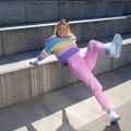 Kobieta pozuje na betonowych schodach, ma na stopach jasnoniebieskie skarpetki w odcieniu Pure Sky i białe sneakersy.