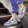 Osoba w jasnożółtych skarpetkach Basic - Banana Shake i kolorowych sneakersach i pomarańczowymi wstawkami stoi na schodach w fioletowych dresach, w słoneczny dzień