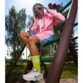 Dziewczyna w różowej bluzie z kapturem i neonowych, limonkowych skarpetkach z napisem „NINETIES”.