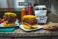 Dwie kompozycje skarpetek ułożone jak burgery, ustawione na talerzach na kuchennym blacie, z pudełkami i sosami w tle.