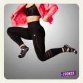 Kobieta w sportowym stroju w dynamicznym wyskoku, ubrana w czarne legginsy z perforacjami, sportowy stanik i różową kurtkę, ma na stopach czarne skarpetki z antypoślizgowym spodem w białe fale oraz żółto-fioletowymi akcentami.