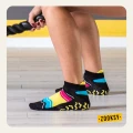 Zbliżenie na stopy kobiety w kolorowych skarpetkach sportowych z antypoślizgowym spodem ABS podczas ćwiczeń z linami na sali treningowej.