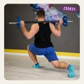 Mężczyzna w wykroku z gryfem na barkach, ćwiczący na jasnej podłodze w sali fitness; na stopach turkusowe skarpetki z żółtym, antypoślizgowym wzorem. Widok od tyłu, z akcentem na stabilność podczas treningu