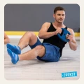 Mężczyzna w niebieskich skarpetkach antypoślizgowych z ABS wykonuje ćwiczenia na mięśnie brzucha z talerzem treningowym na sali fitness – intensywny trening funkcjonalny w odzieży sportowej