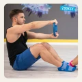 Mężczyzna w niebieskich skarpetkach sportowych z antypoślizgowym spodem ABS wykonuje trening siłowy z talerzem na sali fitness; siedzi na podłodze i koncentruje się na pracy mięśni ramion i brzucha.