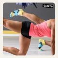 Zbliżenie na dwie osoby ćwiczące na sali fitness w pozycji deski z uniesioną nogą, ubrane w sportowe stroje i niskie, antypoślizgowe skarpetki z kolorowym wzorem w odcieniach żółtego, błękitu i granatu.