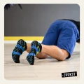 Mężczyzna w pozycji podporu przodem na sali treningowej, w czarno-niebieskich stopkach sportowych z niebieskim nadrukiem antypoślizgowym ABS i wzorem w kształcie fal.