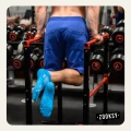 Mężczyzna w niebieskich spodenkach wykonujący ćwiczenie na poręczach w siłowni, w morskich skarpetkach sportowych z siateczką i wyraźną powłoką antypoślizgową ABS na spodzie.