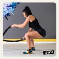 Kobieta w kolorowych skarpetkach antypoślizgowych z ABS marki ćwiczy z linami treningowymi na sali fitness