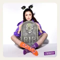 Modelka w halloweenowej stylizacji z kolorowymi skarpetkami mixTURYT. Pomarańczową w oczy potworów i fioletową w czaszki, siedzi za nagrobkiem z napisem RIP.