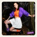 Modelka w halloweenowej stylizacji z pomarańczowo-fioletowymi skarpetkami mixTURY, siateczkowymi rajstopami i kolorowym outfitem pozuje w lesie wśród pajęczyn.