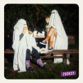 Dwie osoby przebrane za duchy siedzą na ławce i jedzą burgery, mając na sobie kolorowe skarpetki mixTURY Halloween. Pomarańczowe z oczami potworów i fioletowe z czaszkami.