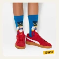 Dziecięce nogi w turkusowych skarpetkach z motywem dziadka do orzechów, w czerwonych sneakersach z białym paskiem.