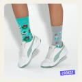 Zbliżenie na dziecięce nogi w sportowych białych sneakersach i świątecznych skarpetkach. Jedna morska w wieńce i kule śnieżne, druga szara w prezenty i gałązki. Kolorowy, wesoły look idealny na zimowe dni.