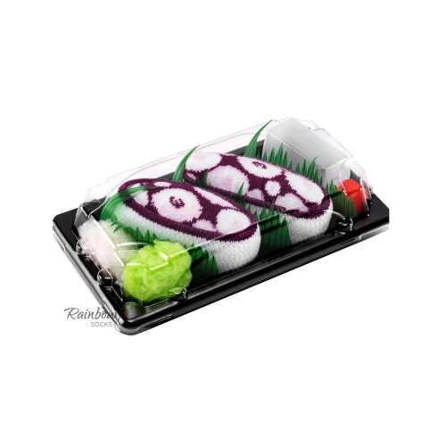 Para skarpet ułożonych w czarnej tackce stylizowanej na sushi, z fioletowo-białym wzorem przypominającym ośmiornicę, przykryta przezroczystą pokrywką.