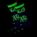 Neonowe skarpetki świecące w UV z intensywnie zielonym wzorem twarzy i abstrakcyjnymi motywami na ciemnym tle.