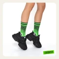 Dziecięce nogi w czarnych sneakersach i neonowo zielonych skarpetkach z graficznym, pikselowym wzorem