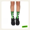 Nogi dziecka w czarnych sneakersach i neonowo-zielonych skarpetkach z geometrycznym, pikselowym wzorem,