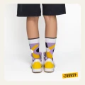 Nogi osoby widziane od tyłu w żółto-fioletowych sneakersach i artystycznych skarpetkach z geometrycznym wzorem w pastelowych kolorach.